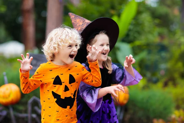 穿着万圣节服装的孩子孩子们不给糖就捣蛋 小男孩和小女孩打扮成巫婆 戴着帽子 手里拿着南瓜灯笼和糖果桶 家庭庆祝活动 — 图库照片