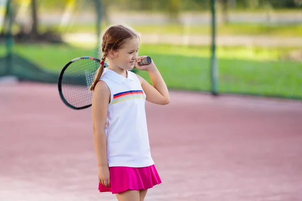 屋内コートでテニスをする子供 スポーツクラブでテニスラケットとボールを持つ女の子 子供のための積極的な運動 子供のための夏の活動 若い子供のための訓練 子供の遊び方 — ストック写真