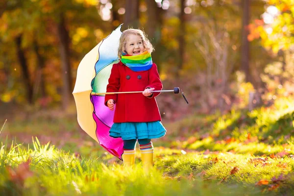 孩子在雨中玩耍 带着雨伞和雨靴的孩子们在秋雨中户外玩耍 小女孩在泥泞的水坑里跳跃 孩子们被秋天的雨天逗乐了 在暴风雨中奔跑的孩子 — 图库照片