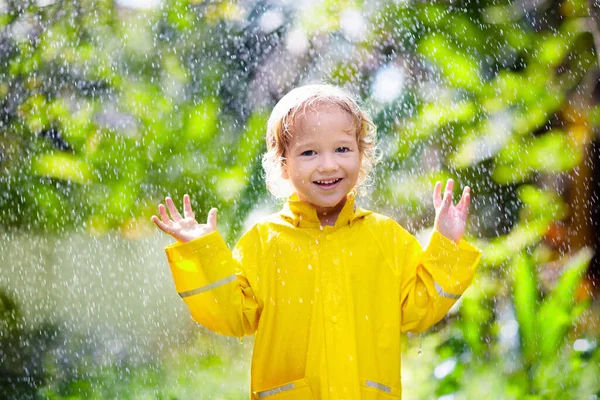 子供は晴れた秋の日に雨の中で遊ぶ 黄色いアヒルの傘で重いシャワーの下の子供 小さな男の子とアヒルの防水靴 ラバーウェリーブーツ 雨天による屋外活動 — ストック写真