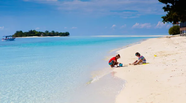 熱帯のビーチで遊んでいる子供 バケツを持って海の岸に広がる小さな男の子 家族の夏休み 砂の城を建てる子供 子供のための水と砂の楽しみ 子供たちが遊ぶ 海の海岸に城を建てる — ストック写真