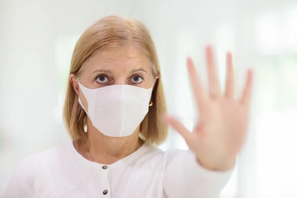 Senior woman wearing face mask during corona virus and flu outbreak. Disease and illness protection. Surgical masks for coronavirus prevention. Sick elderly patient coughing. Ill person.