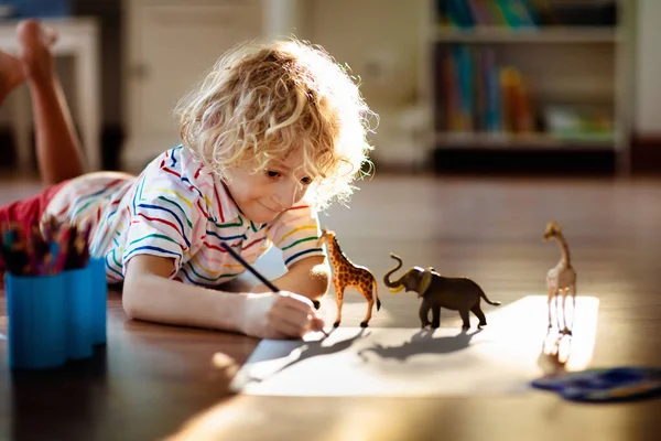 Child shadow drawing animals. Kids play at home. Fun crafts for kindergarten children. Little boy painting giraffe and elephant in sunny bedroom. Games and art during coronavirus quarantine lockdown.