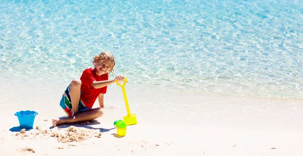 熱帯のビーチで遊んでいる子供たち 子供たちは夏休みに海で泳いだり遊んだりします 砂と水の楽しさ 幼い子供のための太陽の保護 海の岸を走って飛び跳ねる少年 — ストック写真