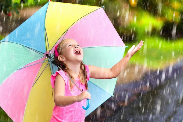 雨の中で遊んでいる子供 大雨の中 傘を差した子供たちが屋外で遊ぶ 少女は最初の春のシャワーに巻き込まれた 雨の秋の天気で子供たちの屋外の楽しみ 熱帯低気圧の中を走る子供 — ストック写真