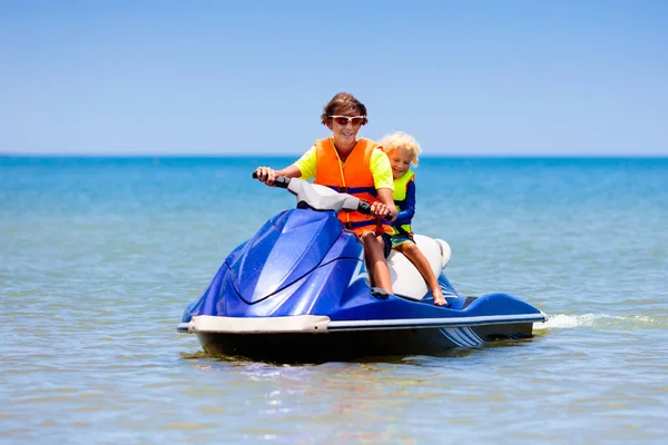 ジェットスキーの家族だ 10代の男の子と小さな子供は水上スクーターでスキーをします 熱帯の海での個人的な水上飛行機に乗っている若い男と子供たち 夏休みだ スポーツと海洋活動 ビーチホリデー — ストック写真