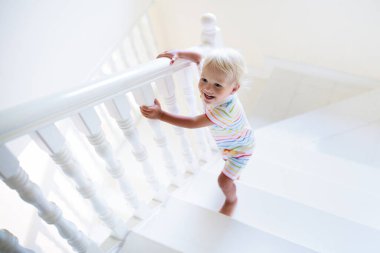 Beyaz Saray 'da merdivenlerde yürüyen bir çocuk. Küçük oğlan güneşli merdivenlerde oynuyor. Aile yeni bir eve taşınıyor. Modern merdivenlerde sürünen çocuklar. Giriş ve oturma odasının içi. Bebek için ev güvenliği.