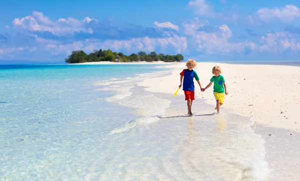 熱帯のビーチで遊んでいる子供たち 子供たちは夏休みに海で泳いだり遊んだりします 砂と水の楽しさ 幼い子供のための太陽の保護 小さな男の子と女の子が走って海の海岸でジャンプします — ストック写真
