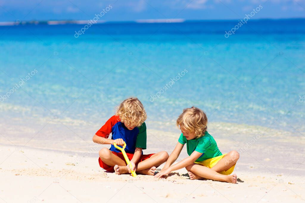 Kids play on tropical beach. Sand toys. Children build sand castle. Child playing at sea on summer family vacation. Water fun, sun protection. Little boy at ocean shore. Travel with kids.