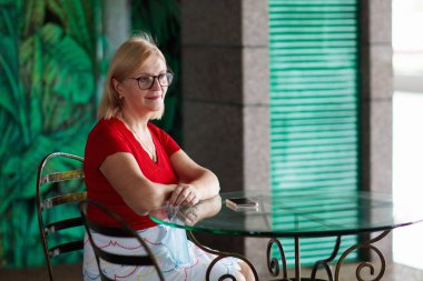 Son sınıf öğrencisi, kafede öğle yemeği yiyor. Restorandaki kadın. Aktif emeklilik. Emekli bir kadın için seyahat ve tatil. Kahvaltıda içmek için sağlıklı meyve suyu..