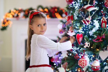 Noel sabahı şöminede bir aile. Çocuklar Noel hediyelerini açıyor. Noel ağacının altında hediye kutularıyla çocuklar. Geleneksel şöminesi olan dekore edilmiş oturma odası. Evde sıcak bir kış günü..