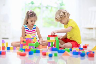 Çocuklar renkli bloklarla oynarlar. Küçük çocuk ve kız evde ya da kreşte kule inşa ederler. Küçük çocuk için eğitici bir oyuncak. Bebek ya da bebek için yaratıcı bir oyun. Anaokulu oyun odasında karışıklık..