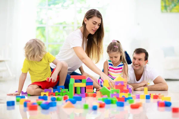 母亲和孩子们玩五彩缤纷的方块 小男孩和小女孩在家里或日托所建塔 家庭在家里 幼儿教育玩具 建筑创意游戏 — 图库照片