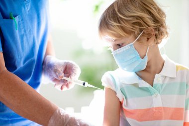 Coronavirus aşısı. Covid-19 aşısı. Çocuk aşılayan doktor. Klinikteki çocuklar. Küçük çocuk grip aşısı oluyor. Çocuk doktoru çocuğu muayene ediyor ve iğne yapıyor. Virüs önleme. Sağlık hizmetleri.
