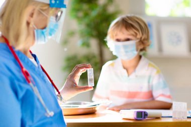 Coronavirus aşısı. Covid-19 aşısı. Çocuk aşılayan doktor. Klinikteki çocuklar. Küçük çocuk grip aşısı oluyor. Çocuk doktoru çocuğu muayene ediyor ve iğne yapıyor. Virüs önleme. Sağlık hizmetleri.