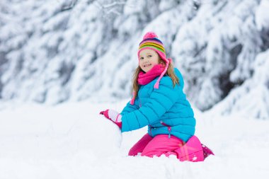 Karlı kış parkında kardan adam yapan bir çocuk. Çocuklar karda oynar. Kar yağdıktan sonra kış bahçesinde kardan adam yapan renkli ceketli ve şapkalı küçük kız. Soğuk kış gününde açık hava eğlencesi.