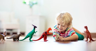 Çocuk renkli oyuncak dinozorlarla oynuyor. Çocuklar için eğitici oyuncaklar. Küçük çocuk fosil ve sürüngen öğreniyor. Çocuklar dinozor oyuncaklarıyla oynarlar. Genç çocuklar için evrim ve paleontoloji oyunu.