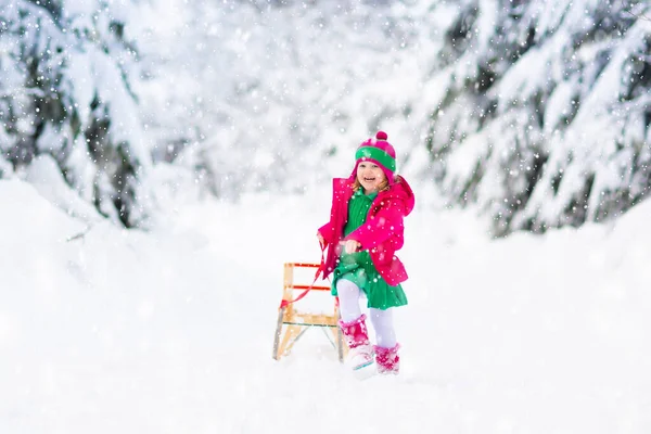 女の子はそりに乗るのを楽しんでいる 子供のそり 幼児はそりに乗っている 子供たちは雪の中屋外で遊ぶ 冬にはアルプスの山々で子供たちがそります 家族のための屋外の楽しみクリスマス休暇 — ストック写真