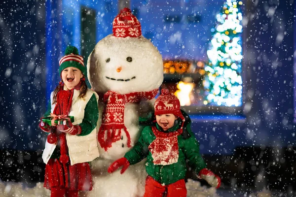 Kids Build Snowman Christmas Eve Children Snowy Backyard Next Window — Stock Photo, Image