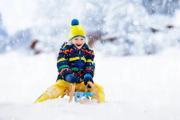 小さな男の子がそりに乗るのを楽しんでいる 子供のそり 幼児はそりに乗っている 子供たちは雪の中屋外で遊ぶ 冬にはアルプスの山々で子供たちがそります 家族のための屋外の楽しみクリスマス休暇 — ストック写真