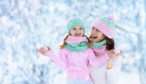 在家庭圣诞假期 戴着针织冬季帽子的母亲和孩子们在雪地里玩耍 给妈妈和孩子的手工羊毛帽子和围巾 给孩子们织毛衣针织外套 雪地公园里的妇女和小女孩 — 图库照片