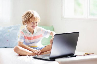 Çevrimiçi uzaktan öğrenme. Bilgisayarlı okul çocuğu öğretmen ve sınıf grubuyla görüntülü konuşma yapıyor. Çocuk evden ders çalışıyor. Dizüstü bilgisayarı ve tableti olan küçük bir çocuk. Coronavirüs salgını.