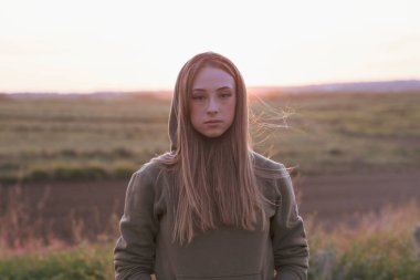 Kapüşonlu bir kız, üzgün düşünceli, doğal bir geçmişi var.