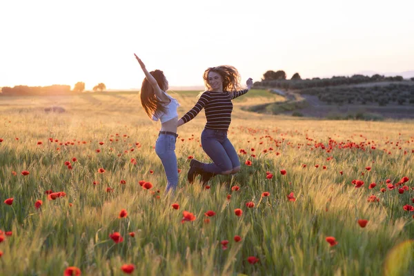 two girls jumping at sunset in the field