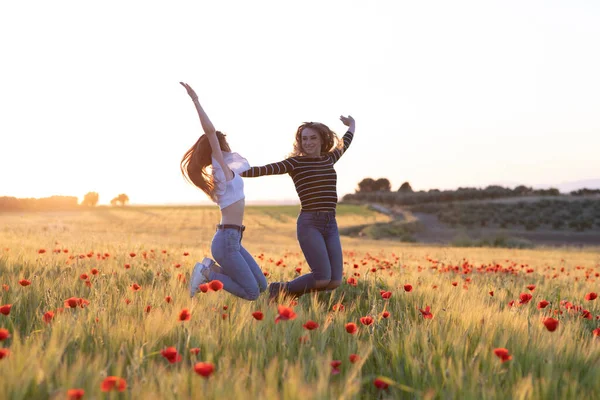 Dos Chicas Saltando Atardecer Campo Amapola — Foto de Stock