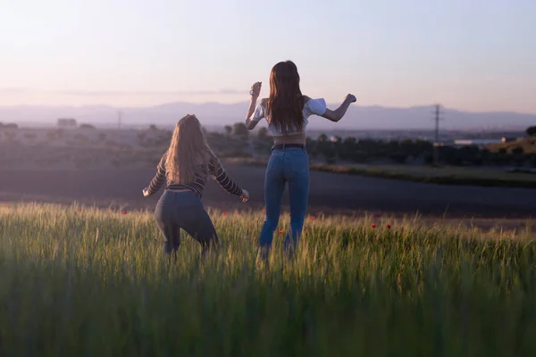 Δύο Κορίτσια Πηδούν Στο Ηλιοβασίλεμα Στο Γήπεδο — Φωτογραφία Αρχείου