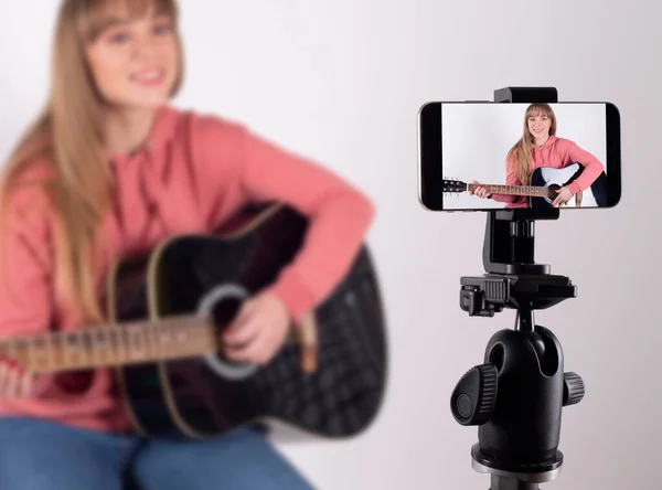girl playing the guitar to share it on social networks. Using the concept of social media influencer for vlog.