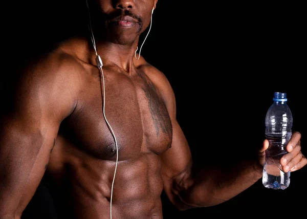 fitness man listens to music and drinks water, black background