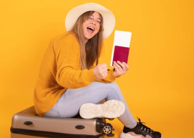 Mutlu kadın portresi, pasaportlu ve çantalı gezgin, sarı arka planda.