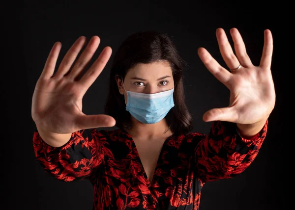 Helps stop global coronavirus infection. woman with raised hands and mask, black background