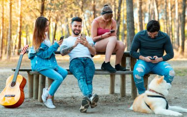 Parkta oturan arkadaşlar, herkes smarptohne kullanır