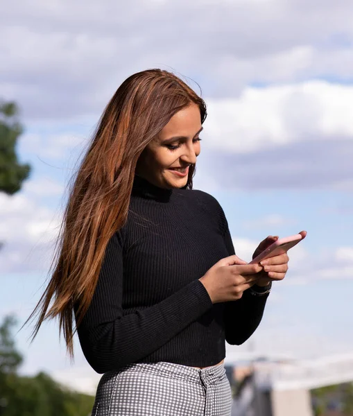 Menina Morena Bonita Sorrindo Enquanto Conversa Com Seu Smartphone — Fotografia de Stock