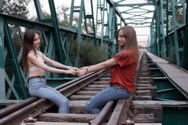 Tren raylarında eğlenen iki kız.