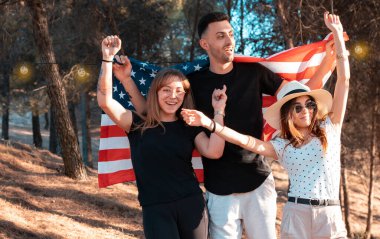 Üç genç erkek Amerika bayrağıyla bir partiyi kutluyor.