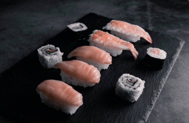 Suşi wasabi ve zencefil ile siyah bir masada siyah bir taş tepside birleşti. Üst görünüm.