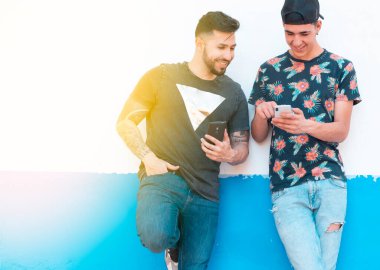 Moda geçmişi olan iki genç çocuk cep telefonlarını kullanıyor.