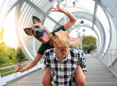 Çılgın ve şık insanlar- T-Rex ve köpek maskesi takan moda çifti, absürd, tatil ve komik moda konsepti -