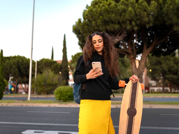 African American Κορίτσι Περιμένει Για Λεωφορείο Ένα Smartphone Ένα Skateboard — Φωτογραφία Αρχείου