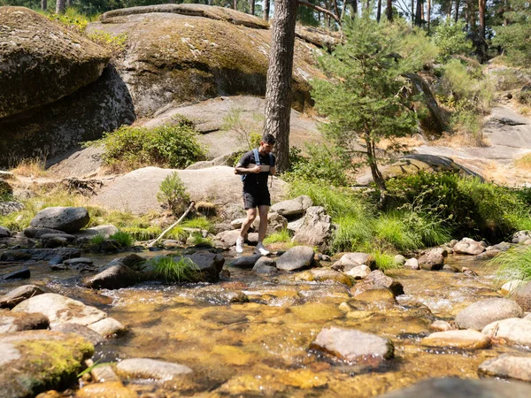 Survival man crossing the river in the mountains with backpack, sunrise or sunset and danger