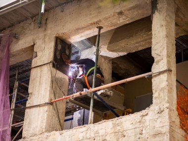 Demir kapıyı kaynak yapan adam, koruma ve kaskla.