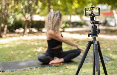 Kadın telefonuyla yoga kursuna kayıt yapıyor, internet üzerinden çalışıyor.