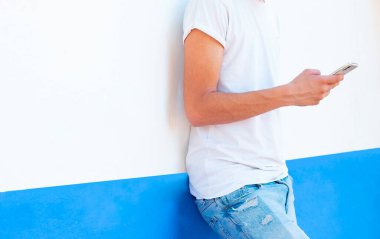 Akıllı telefon kullanarak duvardaki genç çocuk.