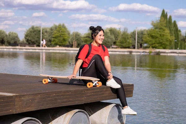 Chica Sentada Muelle Lago Con Mochila Monopatín Mujer Asiática —  Fotos de Stock