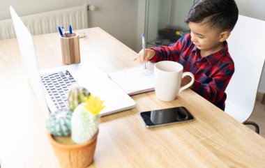 Küçük çocuk evde ödev yapıyor.