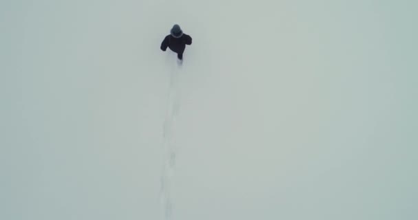 Nohy muže kráčejícího po sněhu se stopami na zasněženém dni. — Stock video