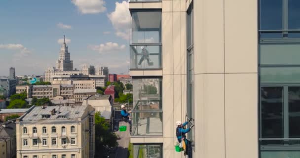 Ablakmosók egy irodaházban. Ipari hegymászó - homlokzati tisztítás. Légi fotózás légdrón — Stock videók